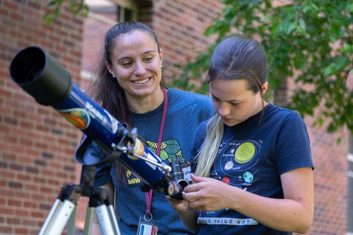 child with teacher and telescope outside